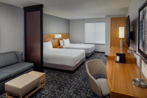 a hotel room with two beds and a couch at Hyatt Place Chicago Midway Airport in Bedford Park