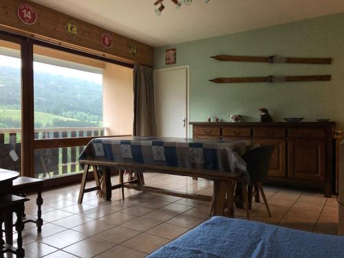 a living room with a table and a balcony at Appartement spacieux tout confort pied des pistes in Lélex
