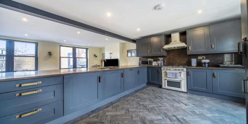 a large kitchen with blue cabinets and white appliances at Elegant 2 Bedroom Apartment in Bromley
