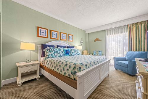 a bedroom with a bed and a blue chair at Villas of Hatteras Landing by KEES Vacations in Hatteras
