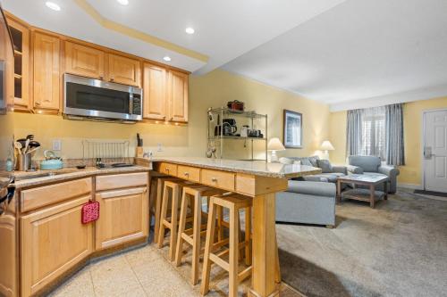 a kitchen with wooden cabinets and a living room at Villas of Hatteras Landing by KEES Vacations in Hatteras