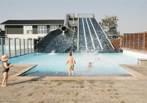 zwei Kinder spielen in einem Pool mit einer Wasserrutsche in der Unterkunft Løkken Klit CARAVANS in Løkken