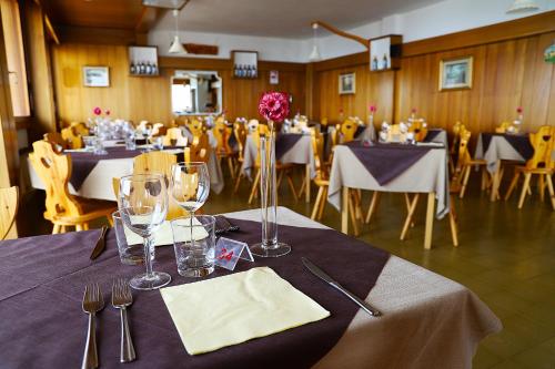 a dining room with tables and chairs with glasses and napkins at HG Hotel La Caminatha in Val di Zoldo