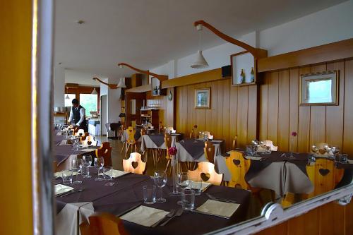 a restaurant with tables and chairs and a man in the background at HG Hotel La Caminatha in Val di Zoldo