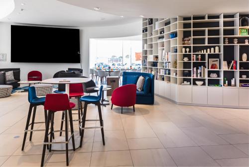 a library with a table and chairs and a tv at Golden Tulip Marseille Euromed in Marseille