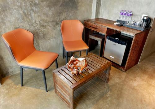two orange chairs and a desk and a table with a statue at The Selene city hotel in Kandy