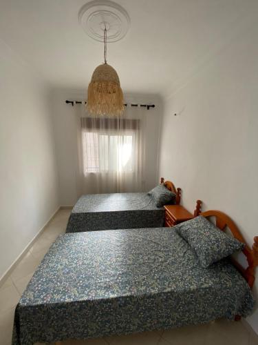 a bedroom with two beds and a chandelier at 5minutes walk to beach apartement- MARTIL - Appartement à 5min à pied de la plage in Martil