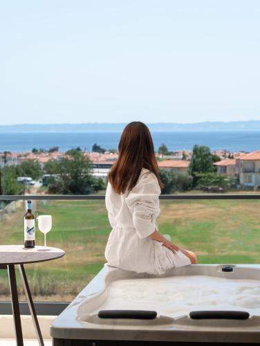 a woman sitting on a bed looking out a window at Anore Luxury Suites in Nikiti