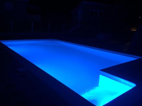 a swimming pool with blue lights in the dark at Apartments Villa Monique in Rogoznica