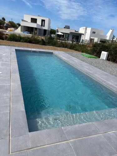 a swimming pool with blue water in front of a house at Casa con vistas al mar con piscina in Porto Covo
