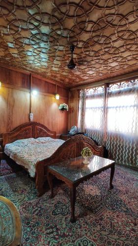 a bedroom with a bed and a table and windows at Smith palace group of houseboats in Srinagar