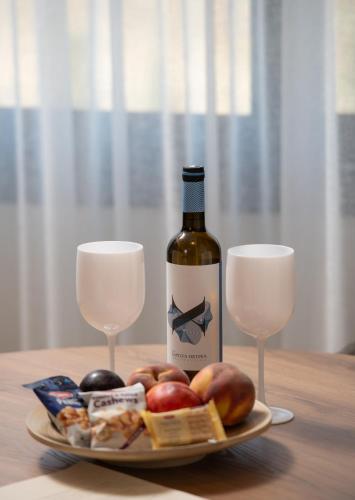 a plate with a bottle of wine and two glasses at Anore Luxury Suites in Nikiti