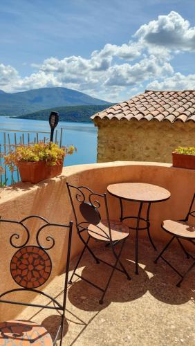 a patio with tables and chairs and a view of the water at chambres d'hôtes Les Fenières in Sainte-Croix-de-Verdon