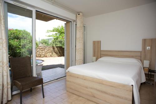 a bedroom with a bed and a sliding glass door at Motel le Vieux Moulin in LʼÎle-Rousse