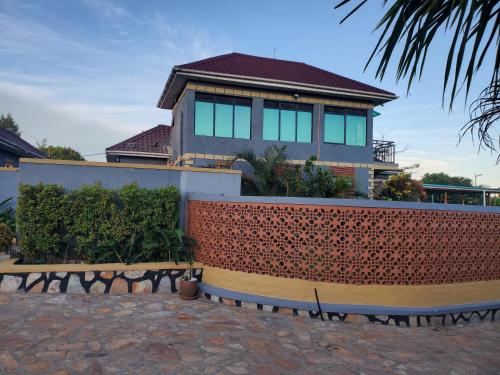 a house with a fence in front of it at Alice Gardens & Campsite in Entebbe