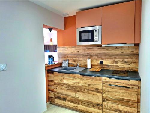 a kitchen with wooden cabinets and a microwave and a sink at Domaine de la Mautanne in Sainte-Tulle