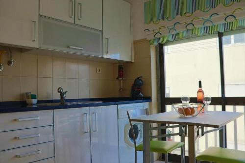 a kitchen with white cabinets and a table and a window at Palace View Mafra in Mafra