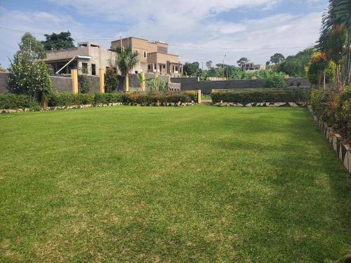 a large lawn in front of a building at Alice Gardens and Campsite in Entebbe