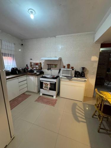 a kitchen with a stove and a microwave at Hostel Casa Jambo Guaruja in Guarujá