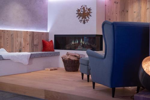 a living room with a fireplace and a blue chair at Posthotel Erlerwirt in Erl