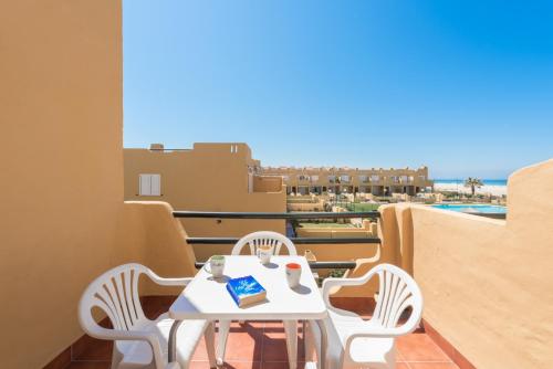 una mesa y sillas en un balcón con vistas al océano en Apartamento Los Lances I, en Tarifa