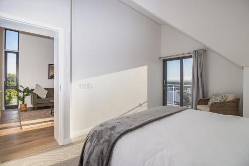 a white bedroom with a bed and a living room at St Francis Links - Elegant, Golfside & Coastal Apartment in St Francis Bay