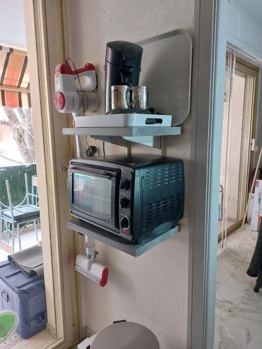 un micro-ondes posé sur un mur avec des étagères dans l'établissement Goelette, à Antibes
