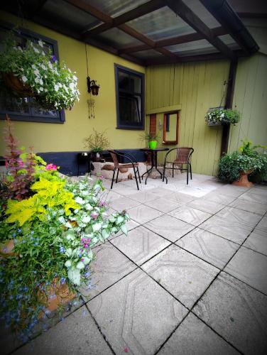 a patio with a bunch of flowers and chairs at STĀRĶA APARTAMENTI in Kuldīga