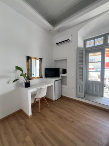 a white living room with a desk and a tv at Douskos Guesthouse in Hydra