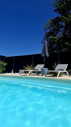 une piscine avec un parasol et deux chaises et un parasol et un parasol dans l'établissement eden & Spa, à Gajan