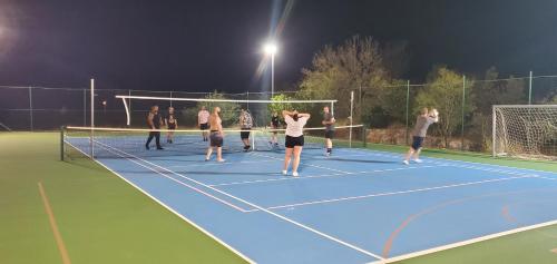 a group of people standing on a tennis court at night at Villa Almas with swimming pool, tennis court, sauna, gym, grill house in Neorić