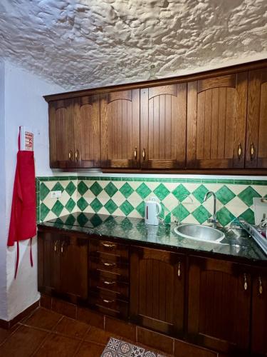 a kitchen with a sink and green and white tiles at Cueva Solaz Galera in Galera