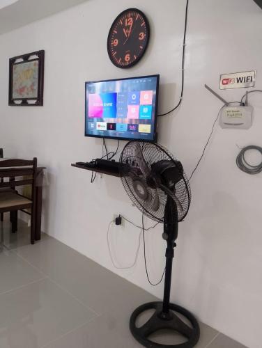 a room with a fan and a television and a clock at The G-Suite Transient House in San Felix