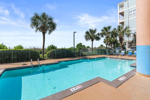 a large swimming pool with palm trees and a building at Seaside Oasis in Myrtle Beach