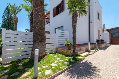 サン・ヴィート・ロ・カーポにあるVilla Giunellaのヤシの木が茂る家の前の白い柵