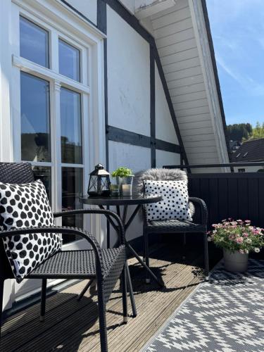 a patio with two chairs and a table on a porch at Ferienwohnung Vierländereck nahe Winterberg in Elpe