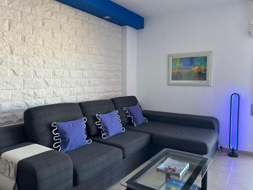 a living room with a black couch and blue pillows at BLAU Apartamento frente a los canales y las puestas de sol de Roses in Roses