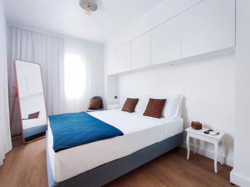 a bedroom with a large white bed with a blue blanket at Casa da Tasquinha in Ponta Delgada