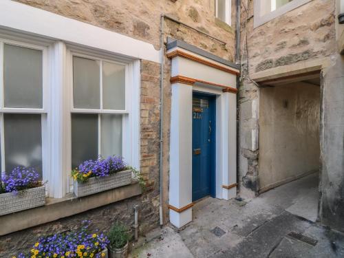 a blue door on a building with flowers in windows at 21A High Street in Jedburgh