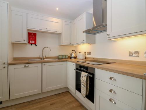 a kitchen with white cabinets and a sink at 21A High Street in Jedburgh