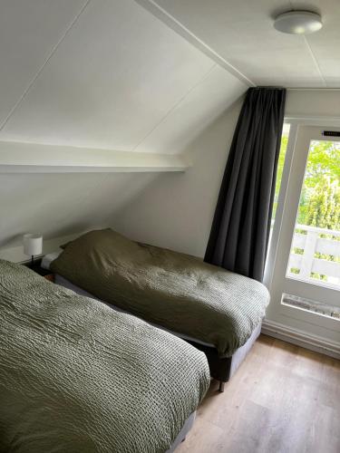 a bedroom with two beds next to a window at Vakantiehuis Lytse Mar in Idskenhuizen