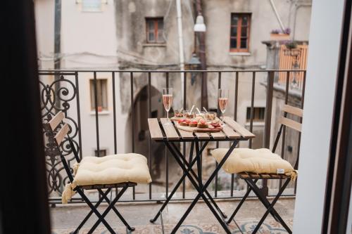 ein Tisch auf einem Balkon mit einem Teller mit Essen und Weingläsern in der Unterkunft La Residenza del Barone in Camerota