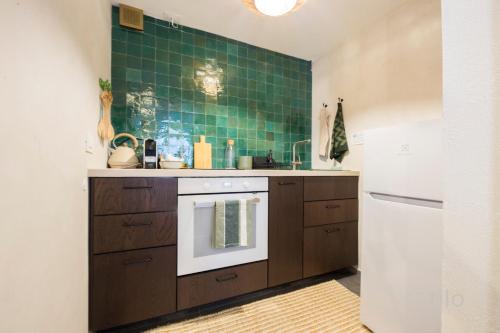 a kitchen with brown cabinets and a green tile wall at Bocadasse Beach| Wifi| Boho Luxury By Tilo in Genova