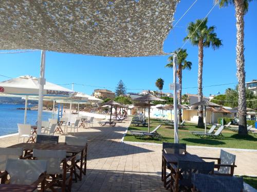 a beach with tables and chairs and palm trees at Miriam Luxury apartment in Zakynthos Town