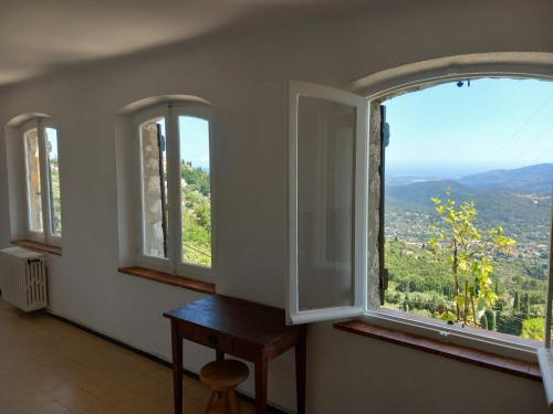 a room with three windows with a table and a view at La villa Haute in Cabris