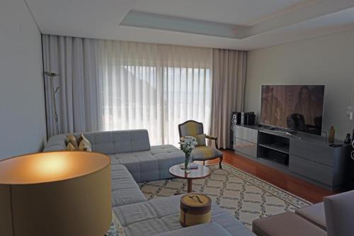 a living room with a couch and a tv at Ocean escape with private pool in Arco da Calheta