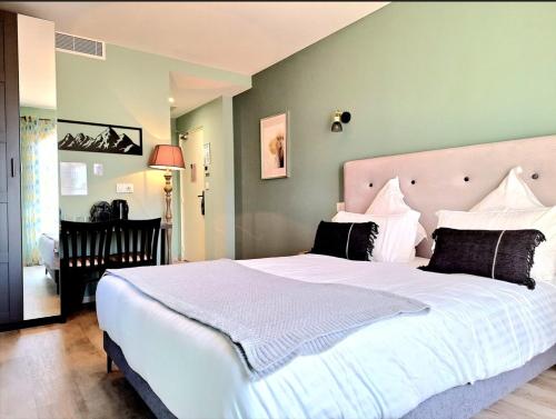 a bedroom with a large white bed with black pillows at Domaine de la Mautanne in Sainte-Tulle