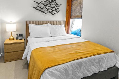 a bedroom with a large bed with a yellow blanket at Captiva Beach Resort (open private beach access) in Sarasota