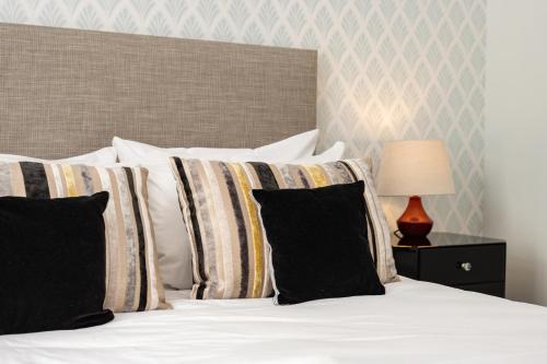 a bedroom with a bed with white sheets and pillows at The Highland Club in Fort Augustus