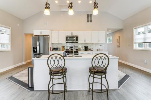 a kitchen with white cabinets and two bar stools at Dock and Backyard Bar Spacious Barnegat Bay Retreat in Waretown